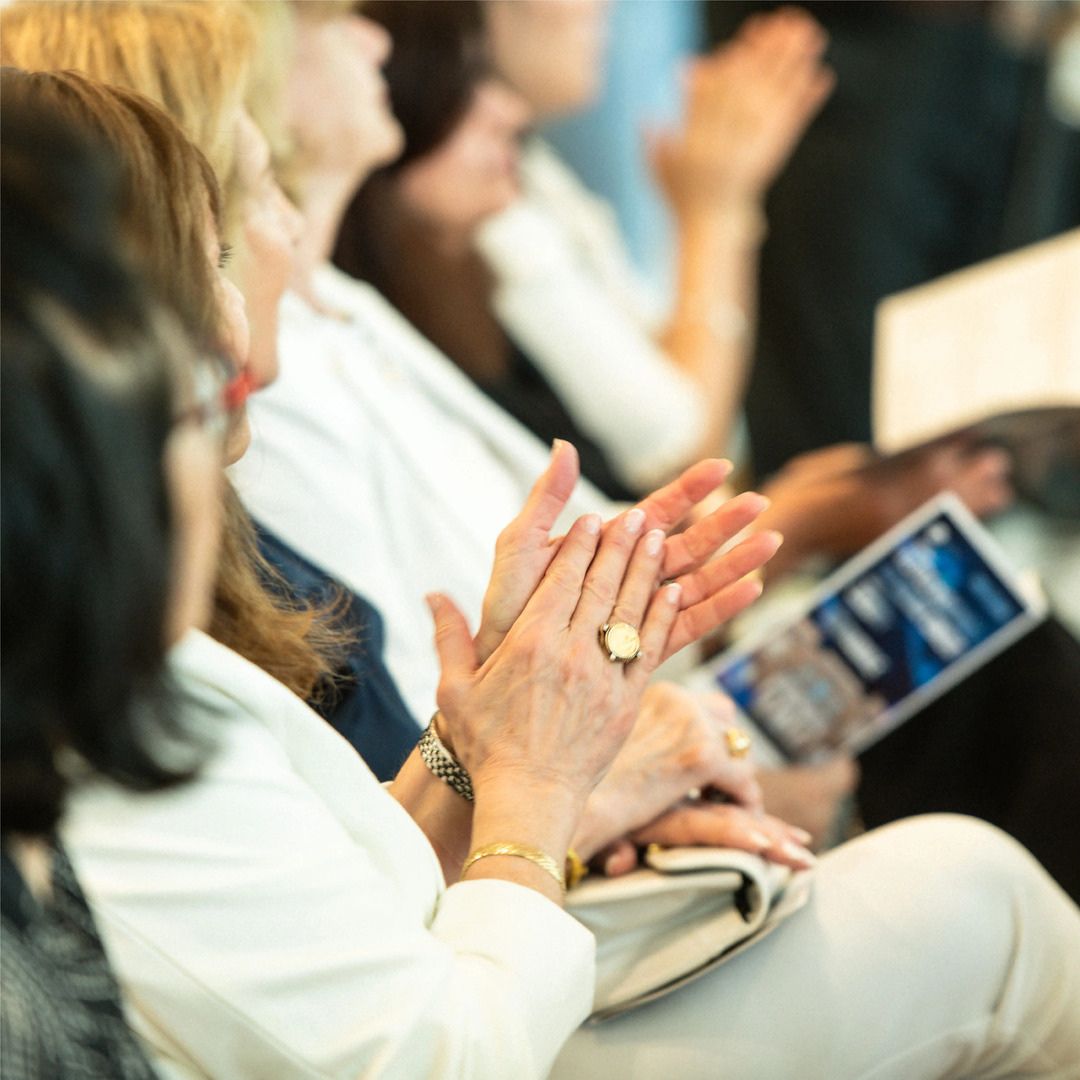 Engaged audience applauding and smiling during a corporate event presentation in Houston.
