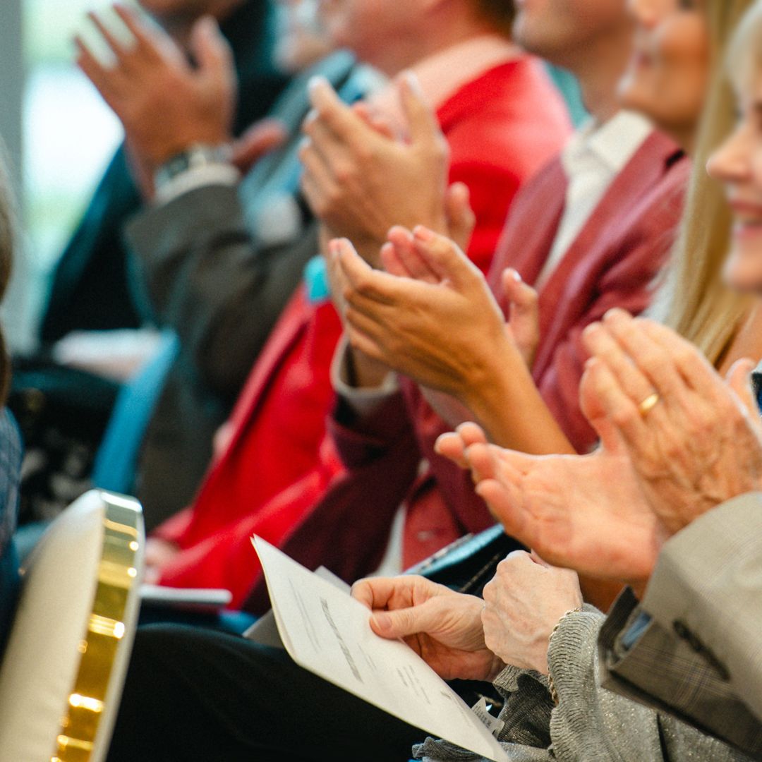 Close-up of event attendees clapping and engaging during a successful corporate presentation at Museo Institute.