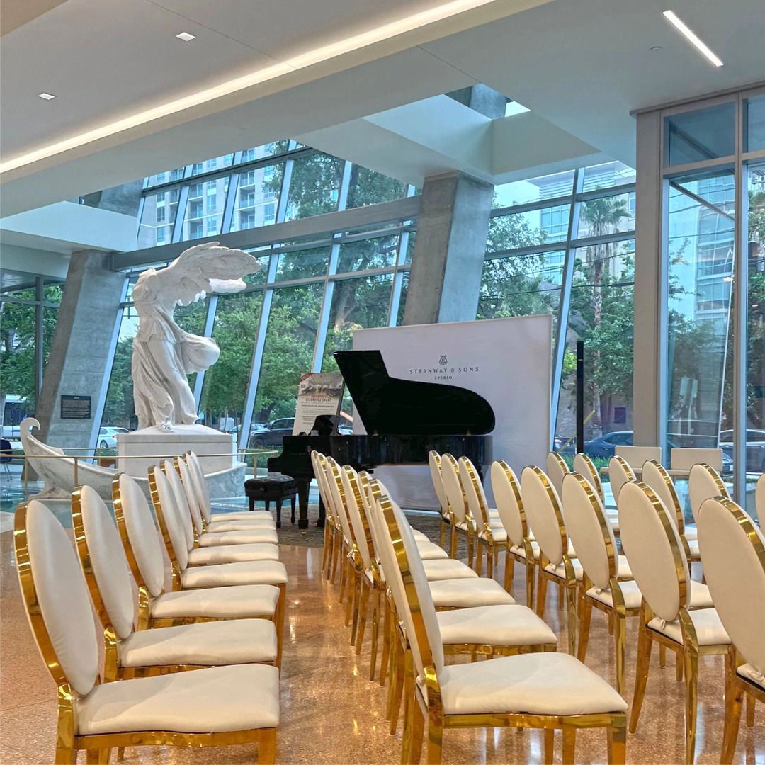 Rows of elegant wooden chairs set up for a presentation in the sunlit Museo lobby.