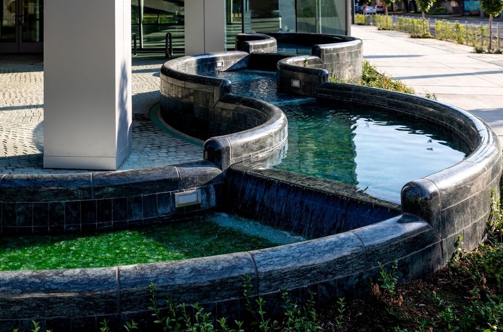Close-up of the elegant serpentine stone water fountain and landscaping at the entrance of the Museo Institute.