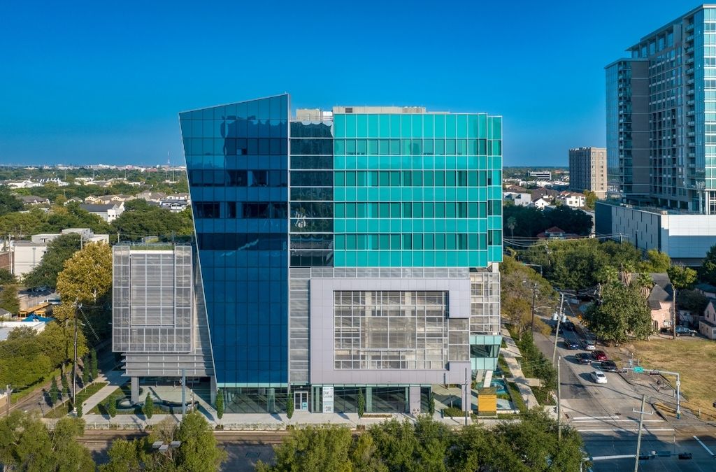 Aerial view of the Museo Houston medical building and the surrounding cityscape at sunset.