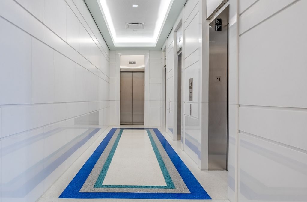 Clean and minimalist white elevator corridor featuring a blue floor runner at Museo Institute.