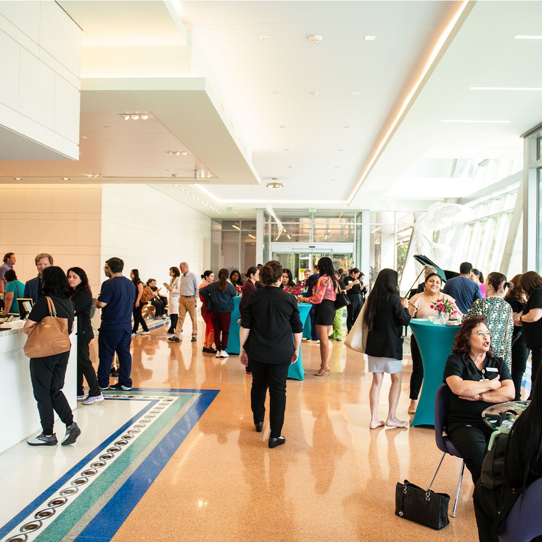 Attendees socializing in the brightly lit, architecturally striking lobby of Museo Houston, showcasing modern design and vibrant floor details.