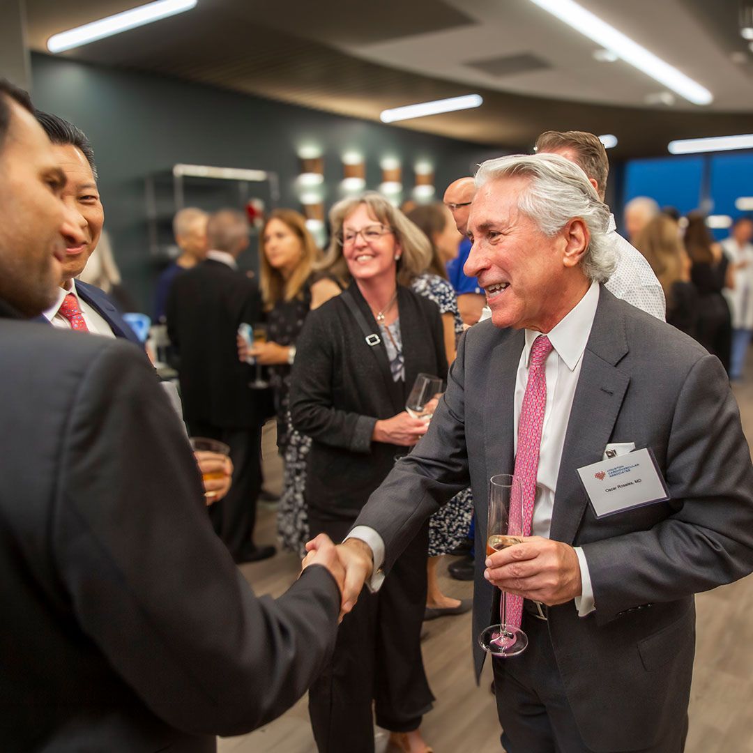 Two professional attendees shaking hands during a milestone celebration event held at Museo Houston.