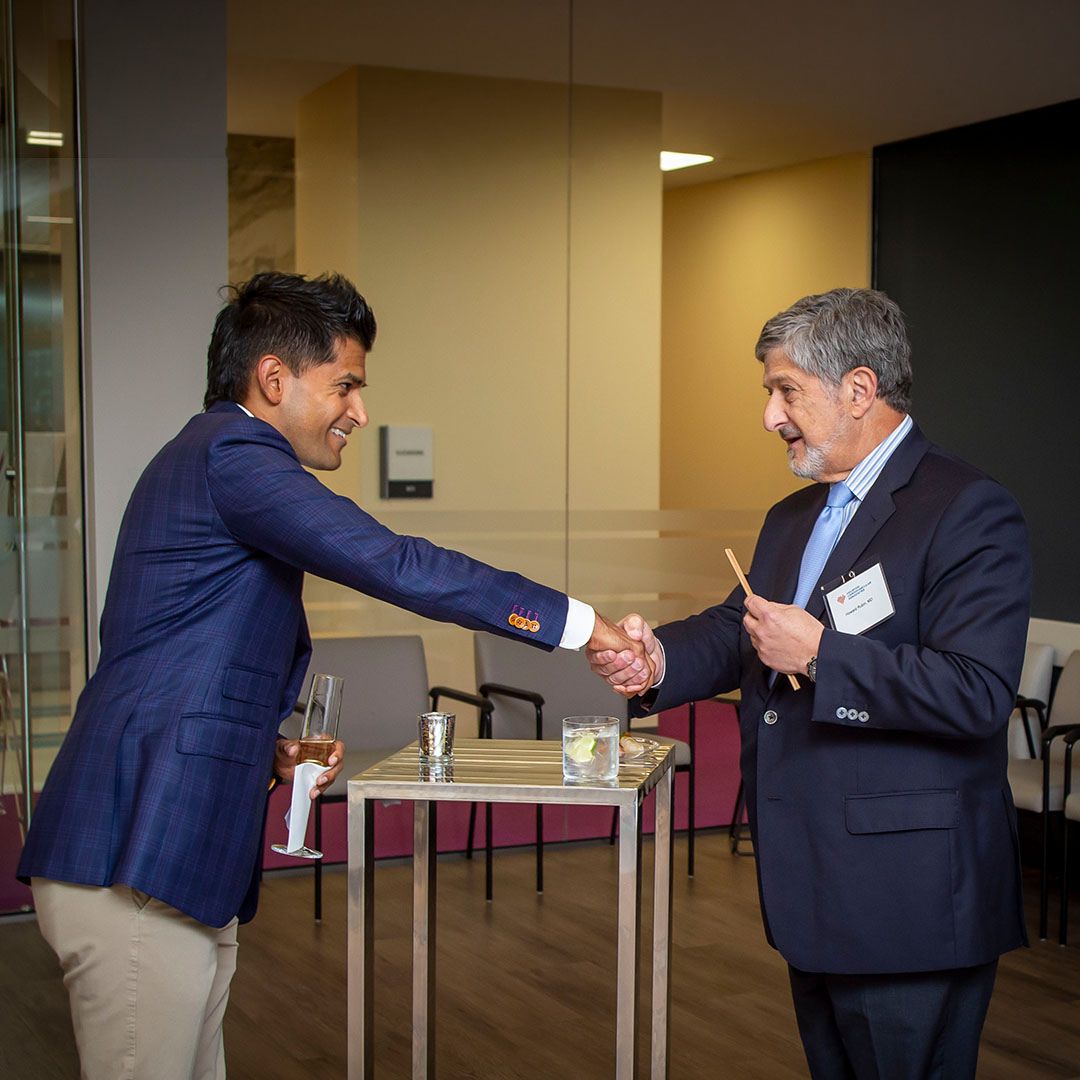 A warm handshake between guests during a community milestone gathering at Museo Houston.