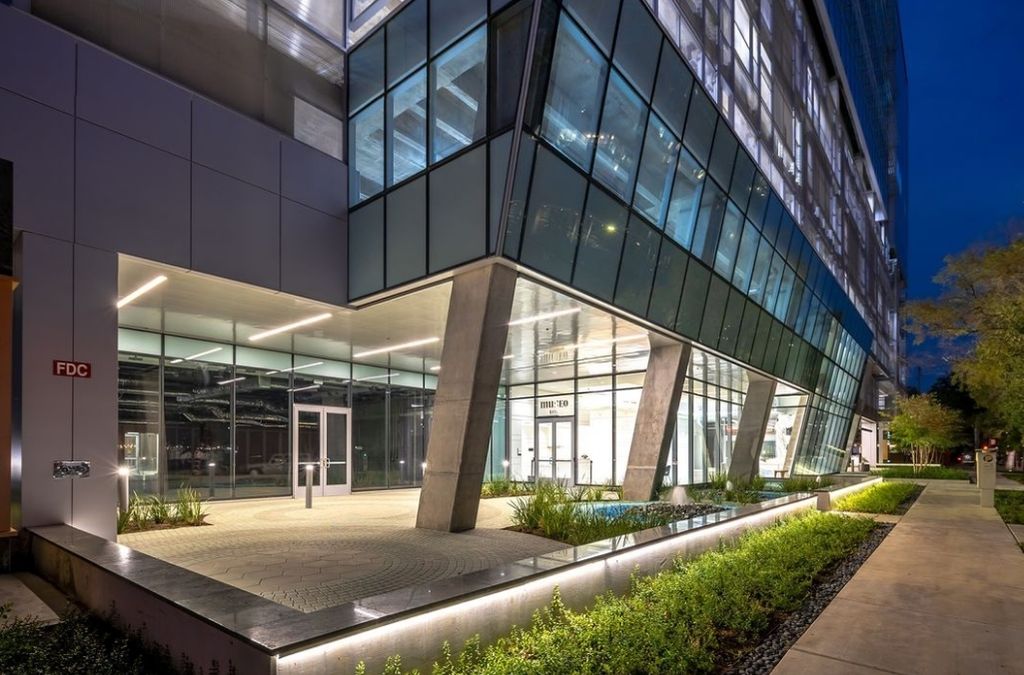 Modern glass facade of the Museo Houston medical building illuminated at twilight.