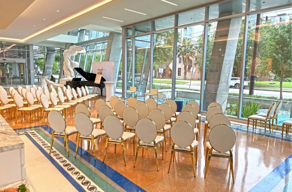 Spacious event and gathering space at Museo Houston set up with rows of chairs, a grand piano, and large windows.