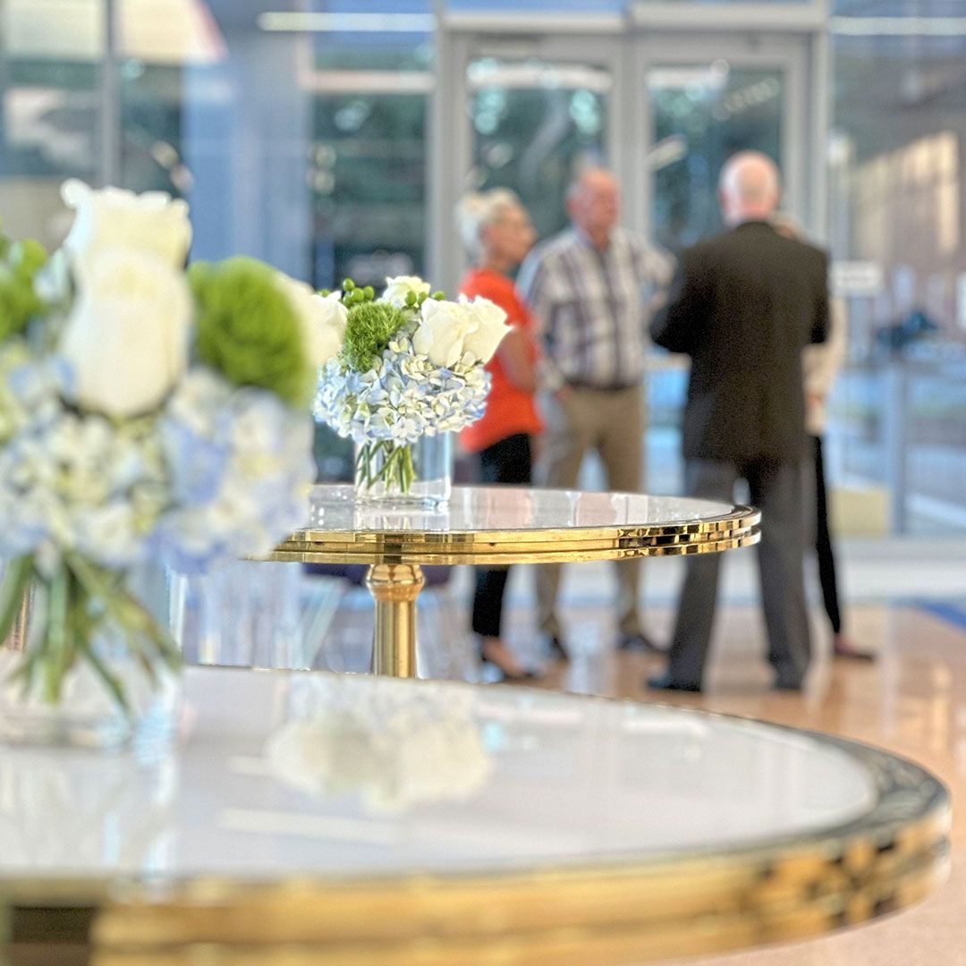 Guests networking near a professional floral arrangement during a milestone event at Museo Houston.