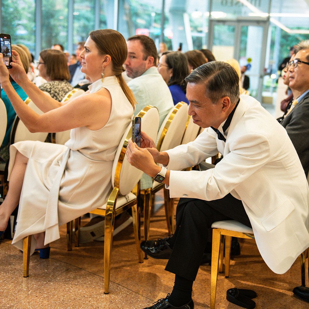 Attendees capturing moments with their phones during a recital at Museo Houston.