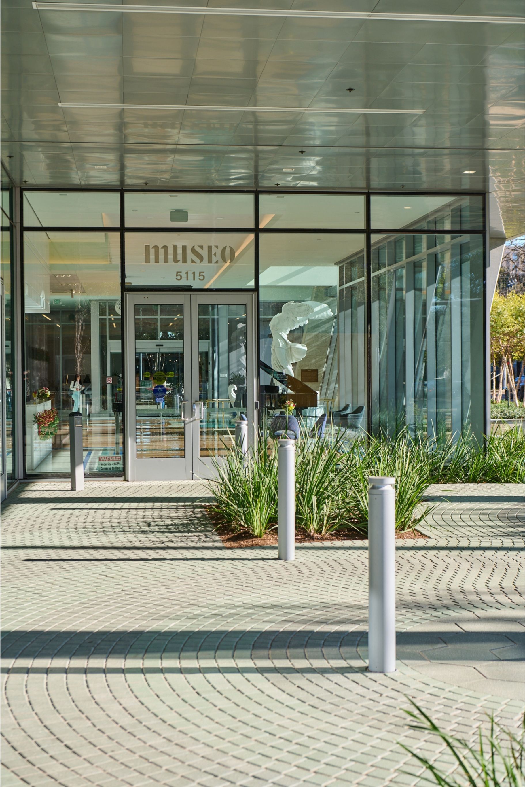 Main glass entrance of the Museo Institute for Medical Arts in Houston with elegant landscaping.