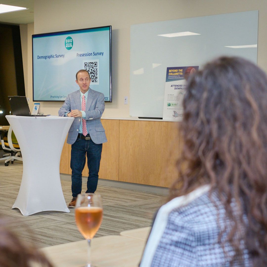A professional speaker in a suit standing at a podium delivering a medical presentation at Museo Houston.