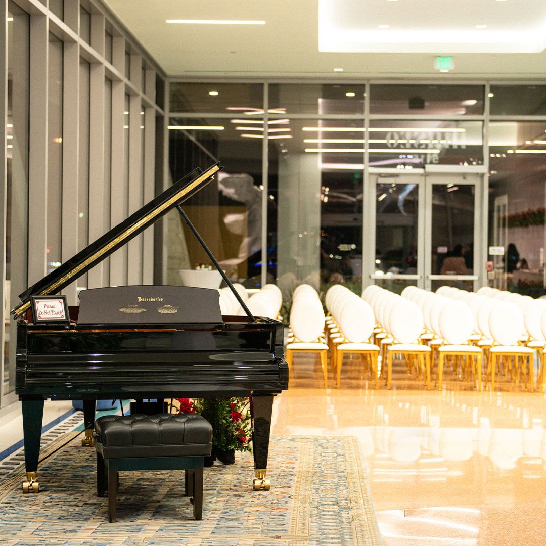 An empty grand piano on a rug, highlighting the sophisticated ambiance of Museo Houston.