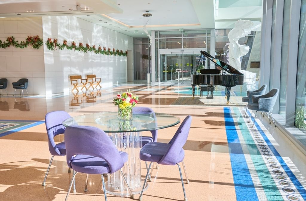 Bright and elegant lounge area at Museo Houston equipped with modern purple seating and a piano.