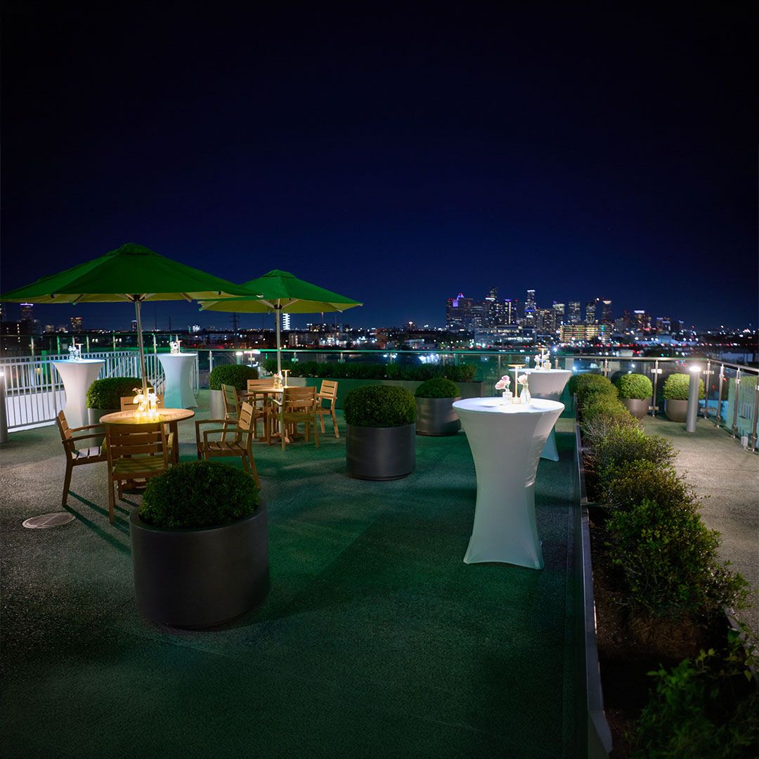 The Museo Houston terrace at night, illuminated with vibrant green ambient lighting for a private celebration.