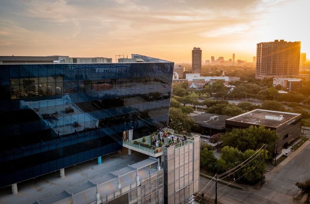 Corporate gathering on the outdoor rooftop terrace at Museo Houston, overlooking the city skyline during sunset.