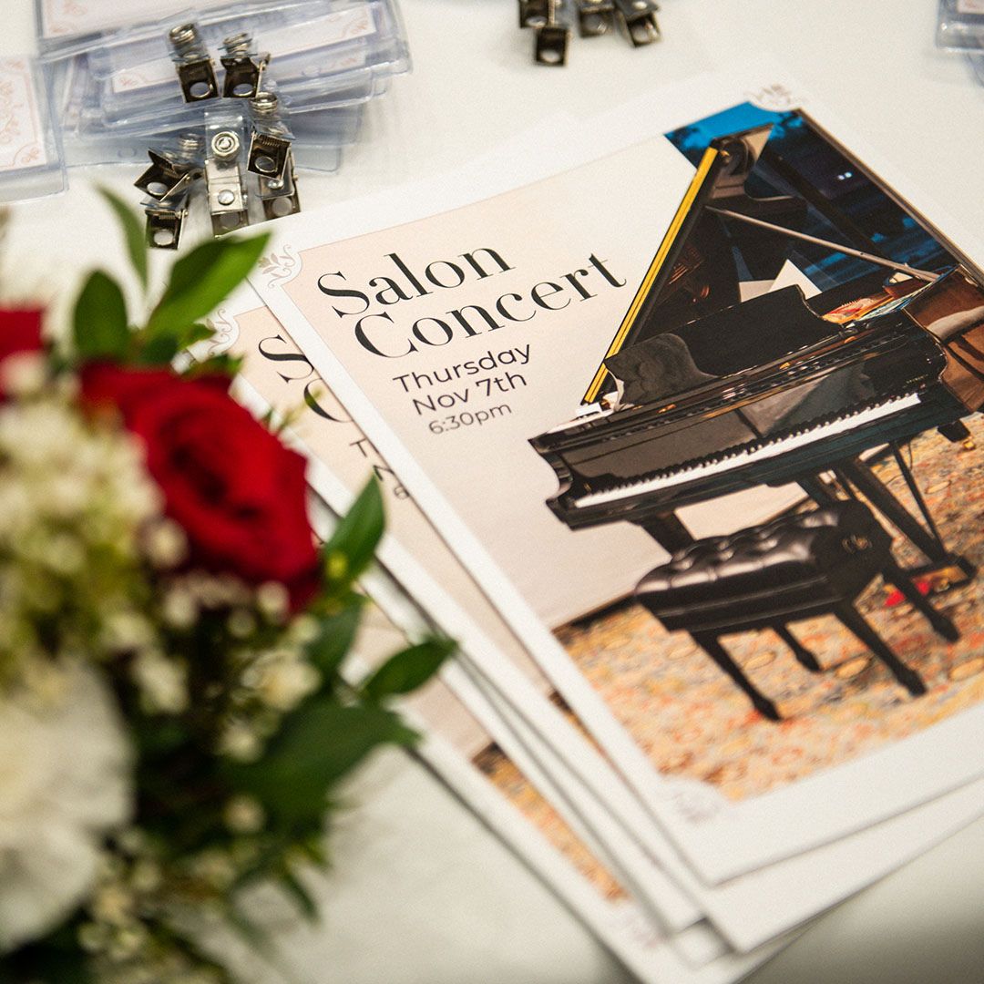 Close-up of Salon Concert programs and floral arrangements at a Museo gathering.