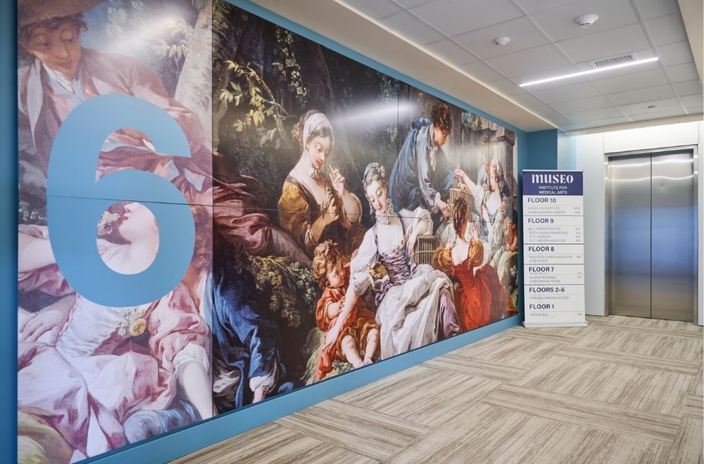 Elevator lobby on the 6th floor of Museo Institute showcasing a large classical renaissance art mural.