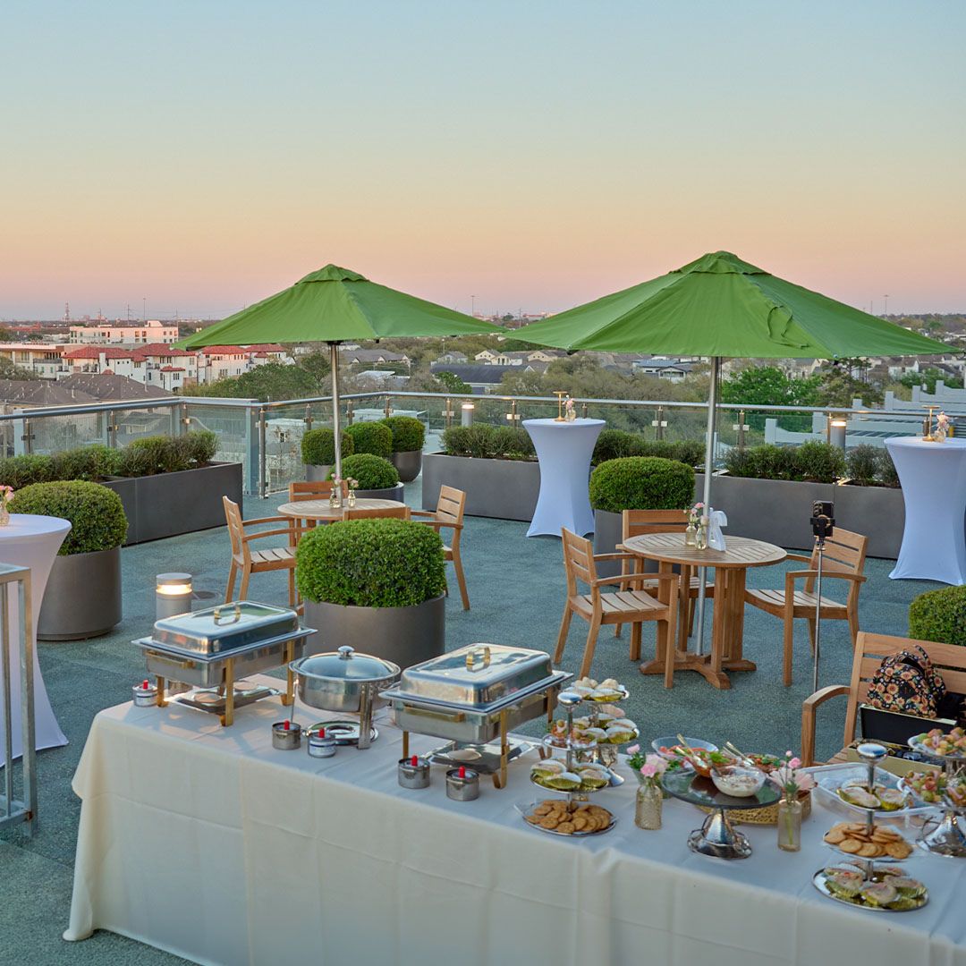 Panoramic view of the upscale outdoor event space at Museo Houston featuring green umbrellas and elegant seating.