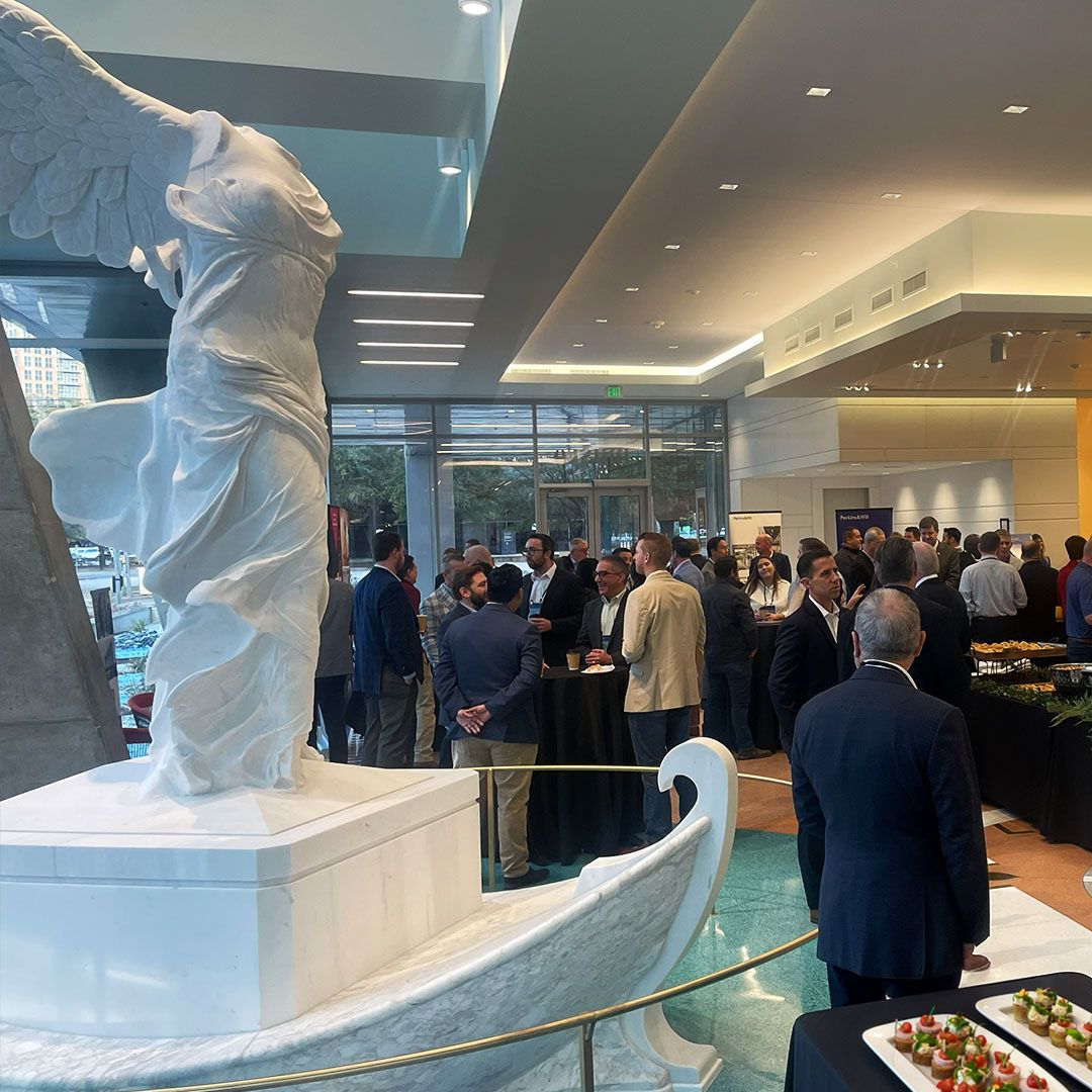 A busy social gathering at Museo Houston with the iconic Winged Victory statue featured as a centerpiece in the main hall.
