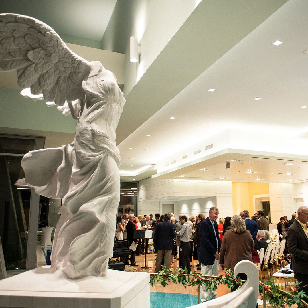The iconic Winged Victory statue at Museo Houston during a crowded cultural event.