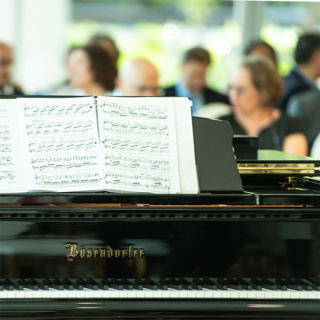 Classical sheet music resting on a grand piano during a live performance in the Museo lobby.